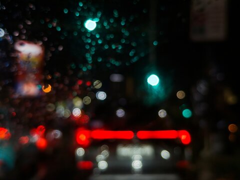 Blur photo of vehicle lights and billboards during rain. Car windows fog up when it rains at night. Abstract lights in the dark background