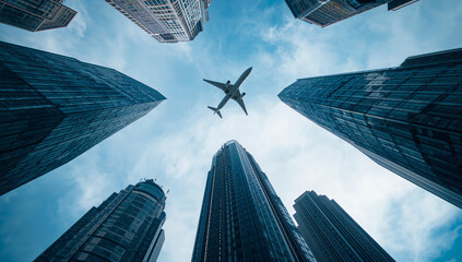 An airplane flying between modern city skyscrapers under a bright blue sky symbolizing progress