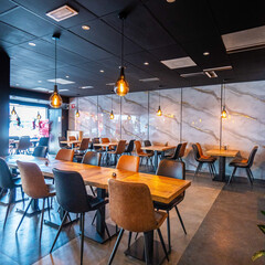 Cozy and modern coffee shop interior with wooden furniture, warm lighting, and large windows overlooking the street, creating an inviting atmosphere