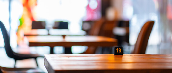 Cozy and modern coffee shop interior with wooden furniture, warm lighting, and large windows overlooking the street, creating an inviting atmosphere