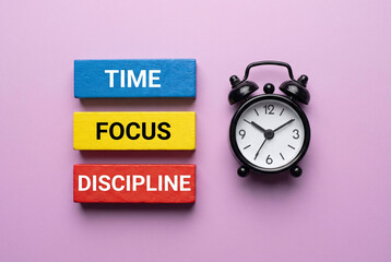 Time focus discipline motivation concept with colorful blocks and black alarm clock on pastel pink background.