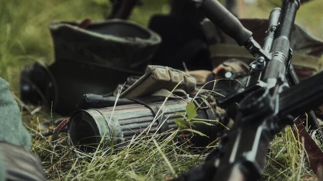 Close-up view of British light machine gun Bren Mk1 or similar ZB-26 ZB-30 resting on green grass. Military infantry equipment of World War II reenactment display. Camouflage gear in background