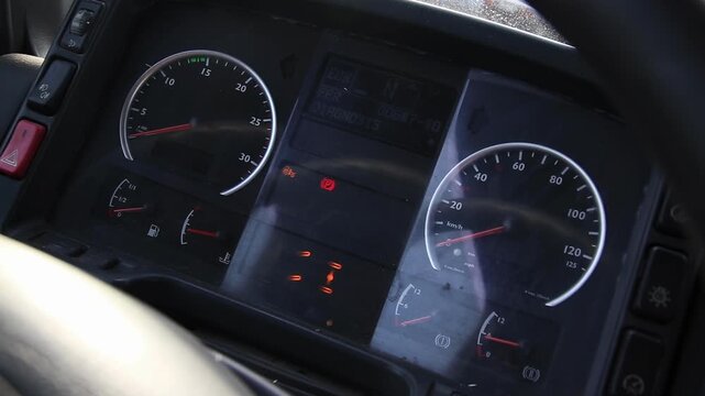 Dashboard of large vehicle or truck featuring instrument panel, speedometer display, tachometer display, various warning indicators, and fuel and temperature gauges.