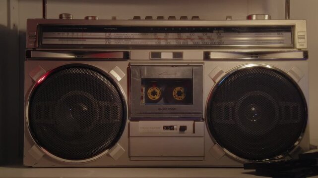 A Man&rsquo;s Hand Carefully Pushes A Cassette Into A Classic 1985 Boombox As He Relaxes In A Living Room Filled With Neon Glow, Retro Comfort, And A Peaceful Atmosphere Perfect For Enjoying Music