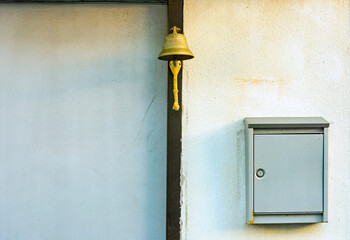 copper bell and a metal letterbox both attached to the front of a house