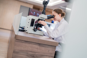 Scientist examines samples through microscope in modern laboratory setting during daytime