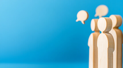 Wooden figures stand out against a blue backdrop, with speech bubbles overhead, symbolizing dialogue, conversation, or discussion, suggesting a collaborative environment.