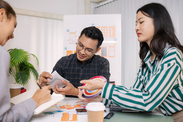 A group of UX/UI designers brainstorming creative ideas together, discussing color palettes and layout concepts for a new mobile application interface in a modern design office.