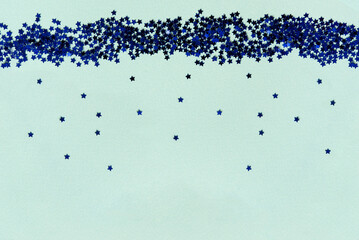 Blue stars of confetti on a blue background. Brilliant sequins. Holiday greeting card. Happy holidays. Minimal, flat lay, copy space. Mockup