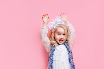 Funny little child girl with a garland around her neck, the concept of new year and Christmas, space for text on the banner, isolated pink background
