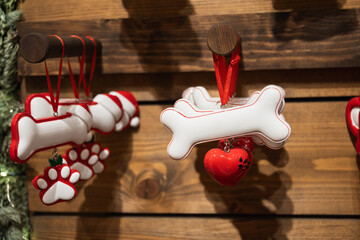 Festive dog themed Christmas ornaments shaped as bone and paw hanging on wooden stall at winter...