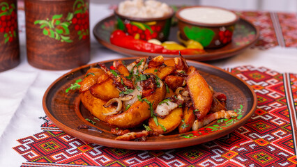 Fried potatoes with meat, salo and onion on a traditional clay plate. Ukrainian cuisine, lunch, homemade.