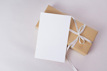 Mockup of a blank white greeting card on simple kraft paper gift boxes, with clipping path.