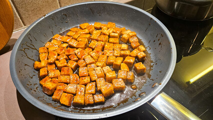 Grilled tofu cubes frying in a pan on the stove — a fresh, organic, plant-based meat replacement coated in a sticky soy sauce. Perfect for meal-prep cooking and easy recipe inspiration.