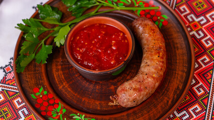 Appetizing homemade grilled sausage with tomato sauce, traditional Ukrainian appetizer, close-up.