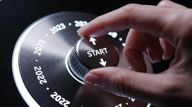 Hand turning a dial towards start concept with years on illuminated display