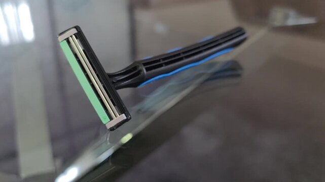 Macro Close-Up of Disposable Triple-Blade Razor on Reflective Glass Surface - Men's Grooming and Hygiene Concept