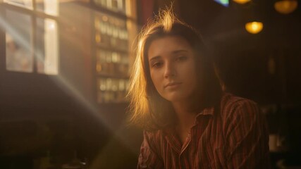 Sunlight urging woman striped shirt necklace turning from window toward camera at cafe, lights