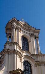 The top of the cathedral with large windows, columns, a cross on top and stone decorations against a blue sky on a sunny day