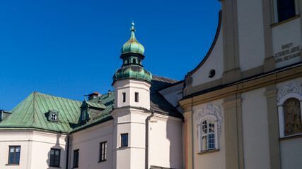 Corner tower of a white church with a green roof. Corner roof of a white church with a round shape and green color against a blue sky background
