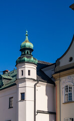 Corner tower of a white church with a green roof. Corner roof of a white church with a round shape and green color against a blue sky background