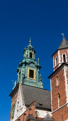 The top of the tower is green. The top of the castle is made of orange bricks against a blue sky background.