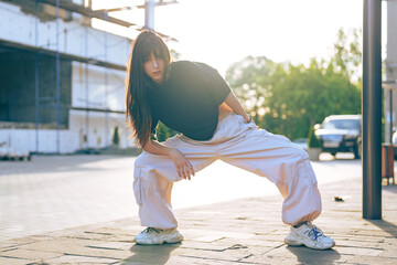Young woman performs street dance in urban environment during sunny afternoon