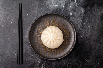 Chinese Steam Bao bun with meat on plate with chopsticks. black background. top view