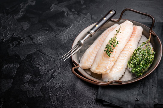 Raw Loin cod fish fillets ready for cooking whitefish in stell tray. black background. top view