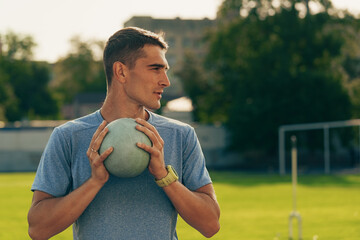 Young athlete prepares to throw shot put on a sunny day at the track and field facility