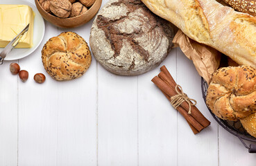 Fresh bread with crispy crust butter and milk at white wooden board in rustic style top view copyspace.