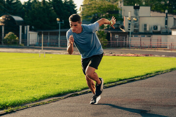 Men engages in sprinting on a track in a sports facility in bright daylight while focusing on speed and technique