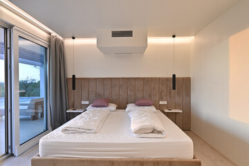 Bright, modern bedroom featuring a comfortable bed, sleek desk, and a large sliding glass door opening to a private balcony with stunning green landscape views, perfect for relaxation and serene