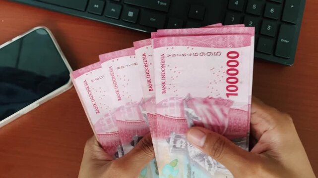 Close-up of female hands managing indonesian rupiah cash.