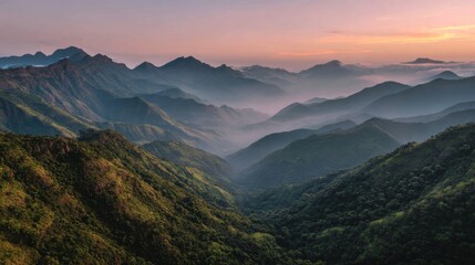 Obraz premium Breathtaking Sunrise Over Lush Mountain Range with Fog Covering Valleys and Peaks Illuminated by Warm Morning Light