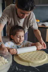 Obraz premium Warm scene of mother instructing daughter in baking at kitchen table