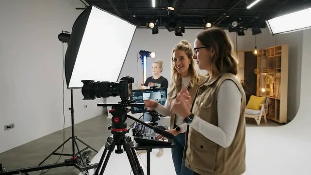 Young women operating professional video camera equipment during a bright studio photoshoot or film production session