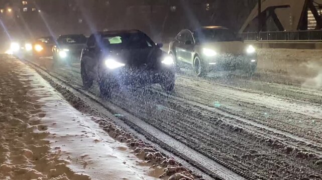 motorists drive along a snow covered street during rush hour