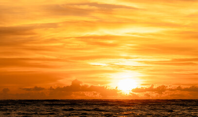 Sunset over sea water in golden hour,Yellow sunrise sky landscape with sun down with gold light on blurry background,Summer nature beach with clouds in autumn,Colorful gradient of beautiful sunlight