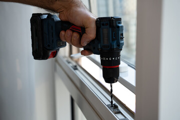 Close-up of a hand operating a cordless drill along a window or frame, ideal for contractor profiles, DIY guides, and tool rental listings
