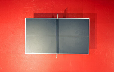 Black table tennis or pingpong table is settle on a red, orange floor of the indoor court stadium for competitions tournament