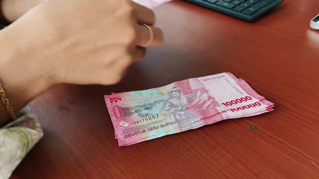 Careful cash counting process using indonesian rupiah notes.