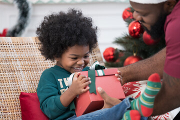 Christmas holiday. Happy family and gift box on Christmas day. African American family opening gift...