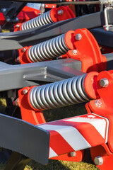 Steel gray spring as part of red heavy agricultural, industrial machine. Technology