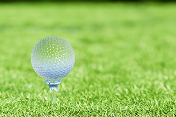 Crystal golf ball on tee on green grass field for golf sport. 3d rendering