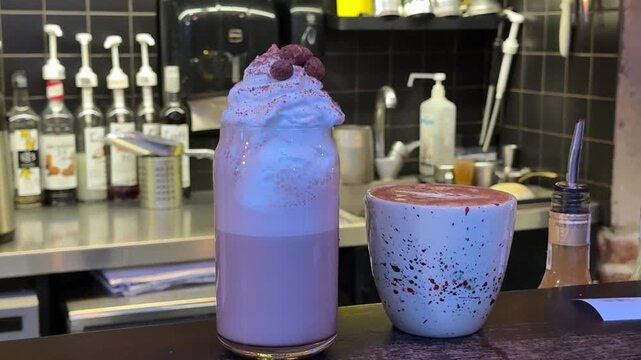 coffee with cream glass of white liquid with a stick in it. The liquid appears to be a type of cocktail or a milkshake. The glass is placed on a black napkin on a counter