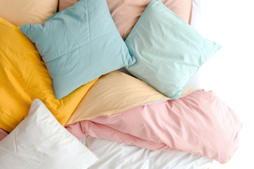 Bedding is spread out on a white surface showing various colors. Soft pillows sit on top with a mix of shades. This setup is ideal for home decor ideas