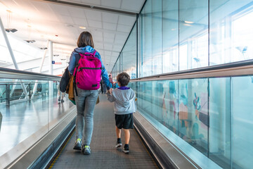 Mother and son walking on moving walkway in airport terminal