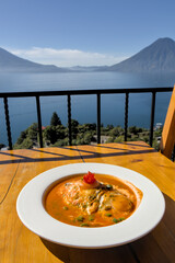 famous ranch egg breakfast dish called huevos rancheros served in a red salsa sauce in beautiful scenic restaurant in lake atitlan guatemala santa cruz la laguna spicy tomato sunny side up volcano sea