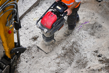 construction worker using a tamping compactor